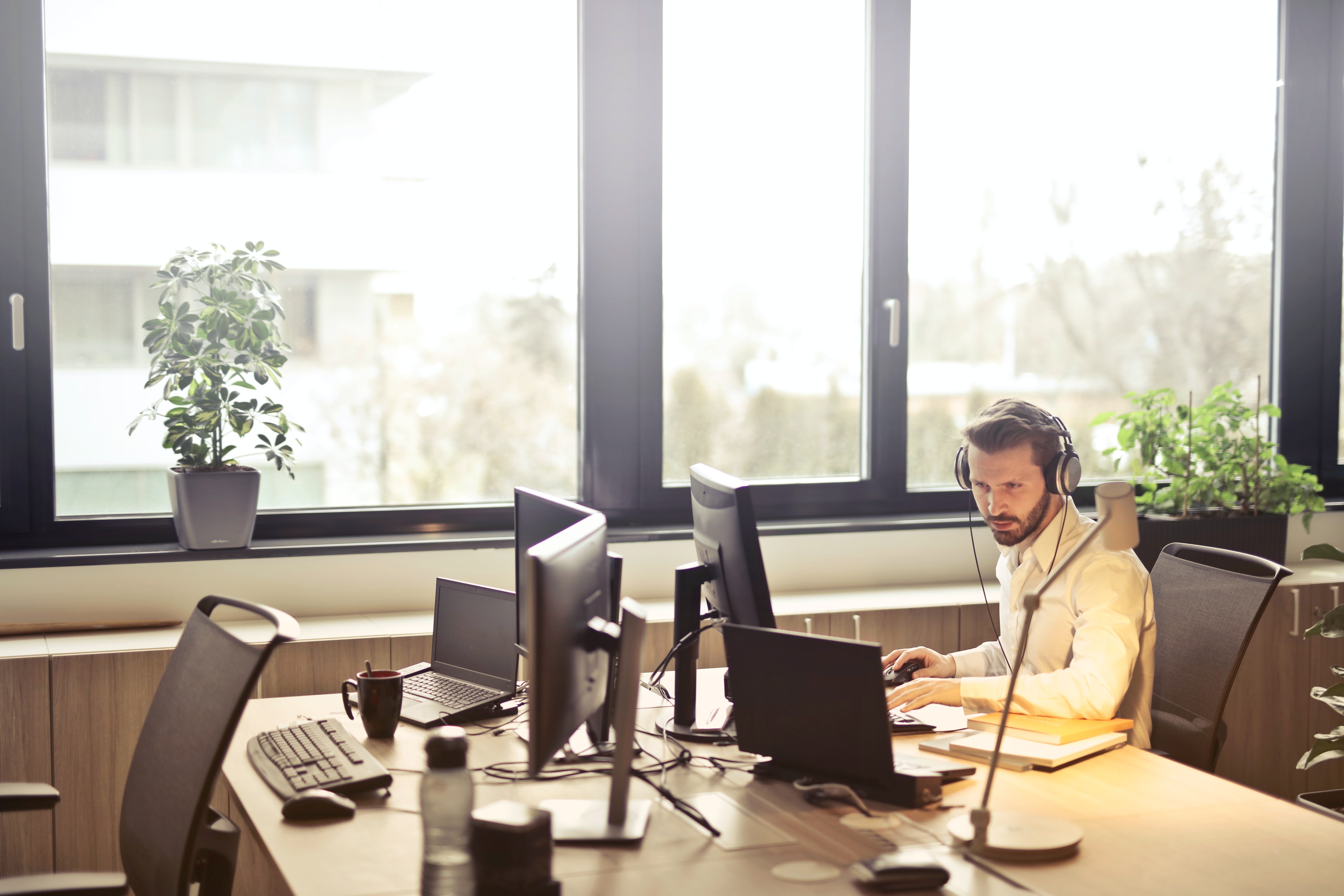 Stock photo of man working at an open work space with laptop and headset.